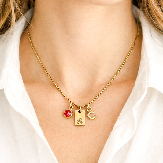 Waterproof Gold necklace with a red heart pendant and 'S' charm on a white shirt