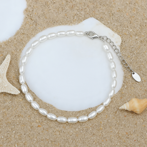 A white pearl waterproof anklet with a gold paperclip chain and a gold extender chain, fastened with a gold clasp.