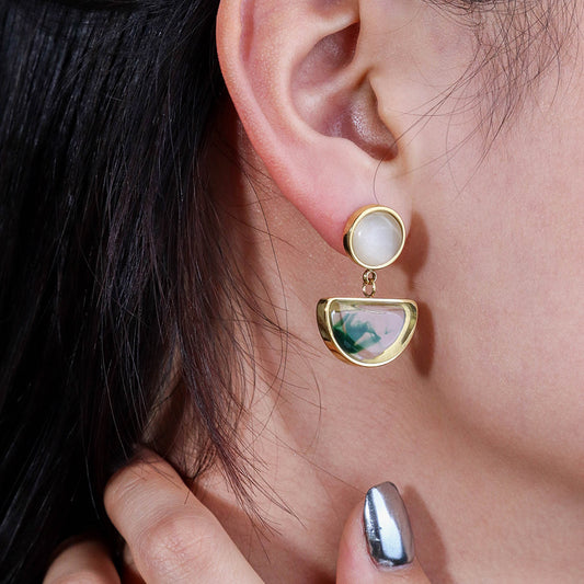 Green and gold statement earrings on model