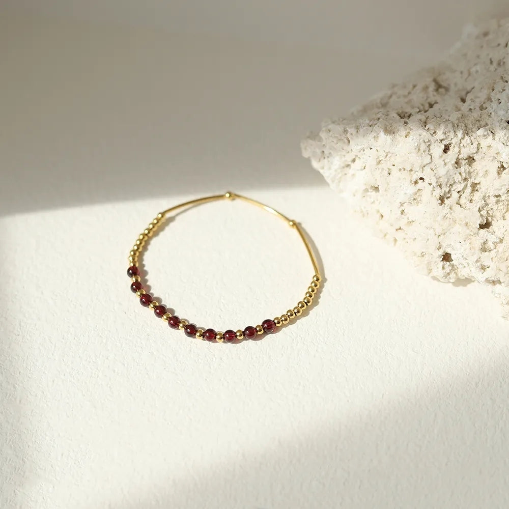 Delicate gold and garnet elastic bracelet by Wyldflower Jewellery